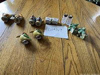 Photo showing all six pairs of vintage salt and pepper shakers arranged on a wooden table with a note card marked Lot #149. Included are ceramic animals, crystal shakers, and wagon model pairings.