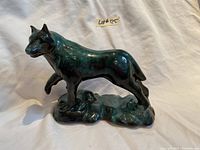 Full side view of ceramic wolf figurine in blue-green glaze, showing animal standing on base.
