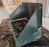 Side angled view of green Coleman propane stove showing two burners and foldable wind guards.