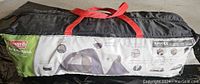 Closed Coleman Elite Montana tent packed inside its black storage carry bag with red handles showing branding and product details.