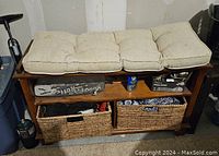 Full view of the wooden hall bench showing beige tufted cushion, wooden frame, two wicker baskets in cubbies, and middle shelf with miscellaneous items.