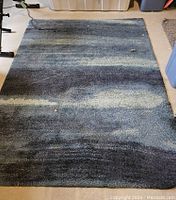 Rectangular blue gradient IKEA rug laid on floor, showing coloration and size.