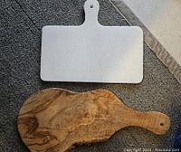 Rectangular marble cheese board and wooden charcuterie board shown from above on a textured surface.