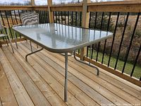 Glass top rectangular outdoor table made with tempered, textured glass and aluminum frame in taupe color.
