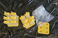 Two yellow popsicle mold sets including holders, bases and extra cups against black background
