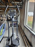 Front view of elliptical machine in basement with windows in background
