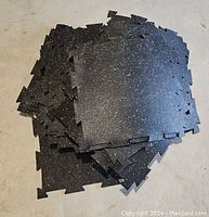 Pile of loose black rubber floor tiles with white specks