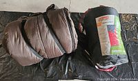 Two sleeping bags laid out, one brown rolled bag and one in black sack with green label
