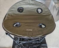 Top view of olive green fabric camping table surface with 4 circular drink holders and ULINE logo.