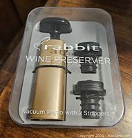 Rabbit wine preserver vacuum pump with 2 black rubber stoppers in clear plastic storage case.