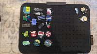 Wide view of all 21 enamel pins on a black pegboard showing pop culture and cat themes