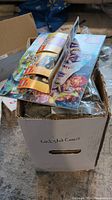Long shot of a white cardboard box labeled 'unlisted comics' filled with bagged LEGO parts and instruction manuals on top.