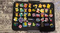 Full view of 43 assorted enamel pins on black pin board showing Pokemon, Zelda, NASA, game logos, and other pop culture pins