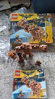 Assembled Clayface LEGO figure alongside original box and instruction manual, showing all components included.