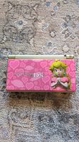 Closed Nintendo DS Lite console with pink Princess Peach skin and heart pattern.