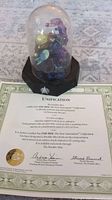 The Star Trek Unification sculpture under a clear dome with a certificate of authenticity placed beneath the dome on a patterned surface.