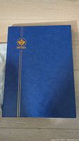 Closed blue Uni-Safe stamp album with gold logo on cover.