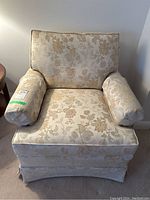 Front view of the floral upholstered armchair showing rolled arms, loose back cushion and skirted base