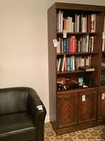 Full front view of bookcase loaded with books and items, showing four upper shelves and two lower doors.