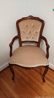Full view of wooden chair with beige fabric seat and tufted velvet backrest with carved wood frame