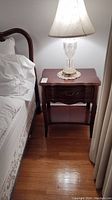 Front view of nightstand beside bed with lamp