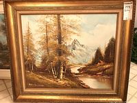 Full view of the framed landscape painting showing the art and elaborate gold frame.