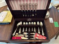 Open mahogany chest showing full spread of knives, forks, spoons and accessories