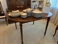 Angled view of assembled table top with dishes, showing wood grain finish and curved end.