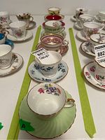Overview of six teacups and six saucers arranged on a table, showing various floral patterns and gold trim details.