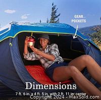 Woman inside the open tent holding a lantern showing spacious interior and gear pockets.