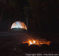 Geodesic dome illuminated at night with firepit in foreground