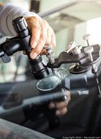 Close-up view of technician using specialized equipment to repair a chip on a car windshield.
