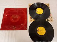 Photo showing two black vinyl records and one red album sleeve with gold "Bee Gees Odessa" text.