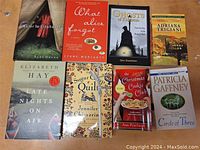 Lot of 9 paperback books laid out on a wooden surface, each showing front covers with titles and authors.