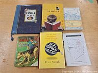 Six books arranged on a wooden surface showing title and cover design to identify each