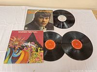 Three vinyl LP records shown with their respective album covers on white cloth background