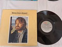 Album cover and vinyl record laid flat on white surface.