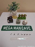 Photo showing all mixed lot items arranged on a white surface including planter, birds, device, box, baseball, sign, coins, and letter opener