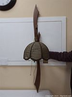 Full side view of the retro wicker wall lamp mounted on the wall with a curved wooden backplate and scalloped wicker shade.