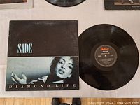 Photo showing Sade Diamond Life album cover and vinyl record out of sleeve.