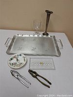 Full lot showing all items arranged: metal serving tray, vintage goblet, vase, decorative plate, glass tray, and two nutcrackers.