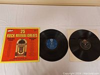 Two vinyl LPs photographed on white cloth; one has original 25 Rock Revival Greats cover showing jukebox and song list, the other LP shown without cover.
