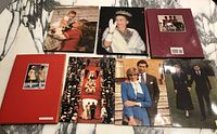 Seven books laid out on a gray marble surface. Top row has three books with royal figures on covers. Bottom row has four books featuring royal wedding and other official portraits.