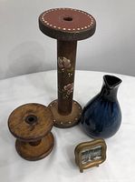 Lot contents showing blue ceramic vase, two wooden spool candleholders including one with floral toile painting, miniature framed landscape painting with stand.