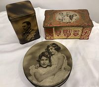 Photo showing all three tins together on a white background with clear view of each tin's portraits and designs