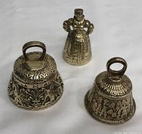 Three solid brass hand bells shown together on white background, displaying overall shapes and designs.