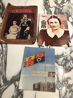 Three vintage magazines and booklets laid out on marble surface including 1937 Royal Coronation souvenir album featuring King George VI and Queen Elizabeth on cover, Edward VIII abdication crisis magazine with woman's black and white portrait cover, and 'Our Queen is Crowned' booklet with flag image.