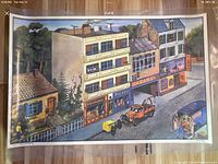 Photo of the street side of the double-sided poster showing buildings, vehicles and signage, in vibrant colors