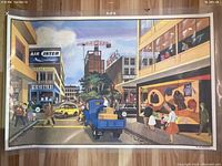 Photo of the poster side showing a busy urban street intersection including a blue truck, pedestrians, street signs, and buildings with vintage signage.