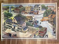 Photo of 'Le Village' side showing detailed village scene with buildings, vehicles and people.